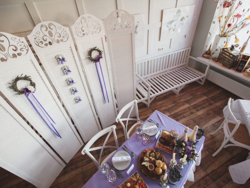 Dining table setting at Provence style, with candles, lavender, vintage crockery and cutlery, closeup.