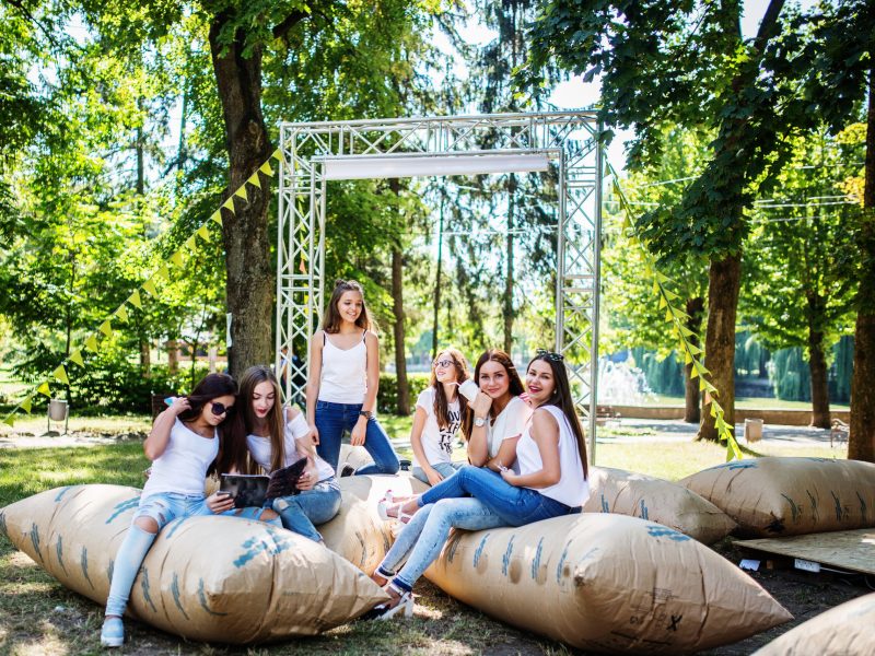 Six young happy girls having fun on giant pillows in the park. Six young happy girls having fun on giant pillows in the park.
