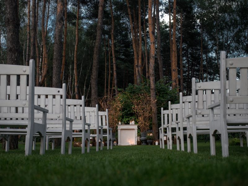 Look from below at white benches standing before place for wedd Look from below at white benches standing before place for wedding altar in the garden