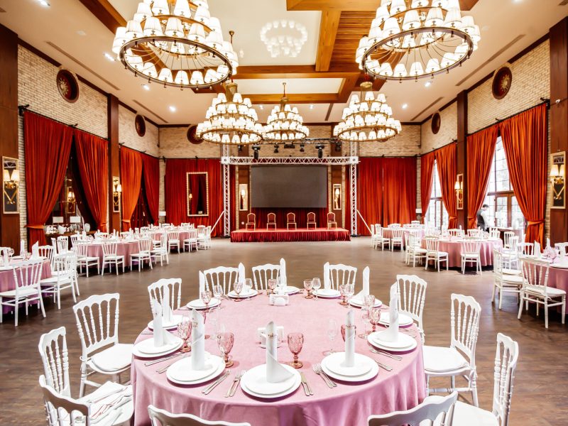 restaurant hall with small stage monitor red curtains brick walls white napoleon chairs
